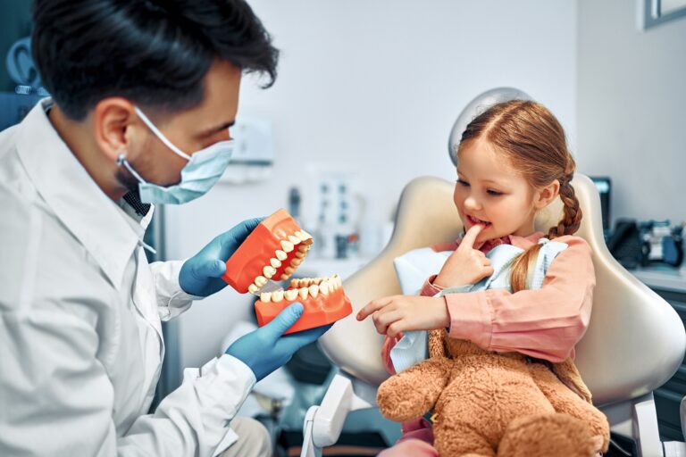 Dentist for kids speaking gently with a young child at their first dental visit
