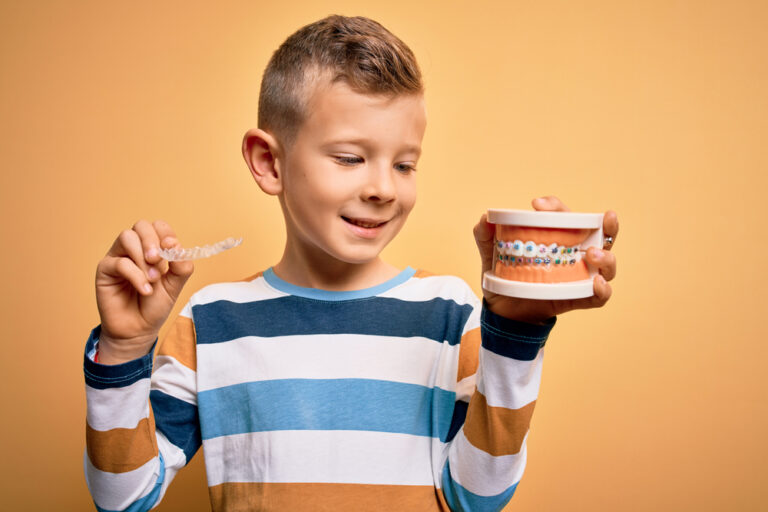 Child smiling with dental braces – comparing metal braces vs. clear braces for kids