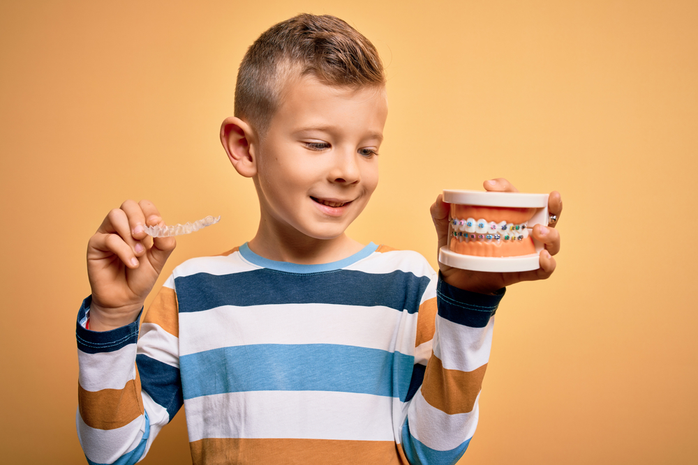 Child smiling with dental braces – comparing metal braces vs. clear braces for kids